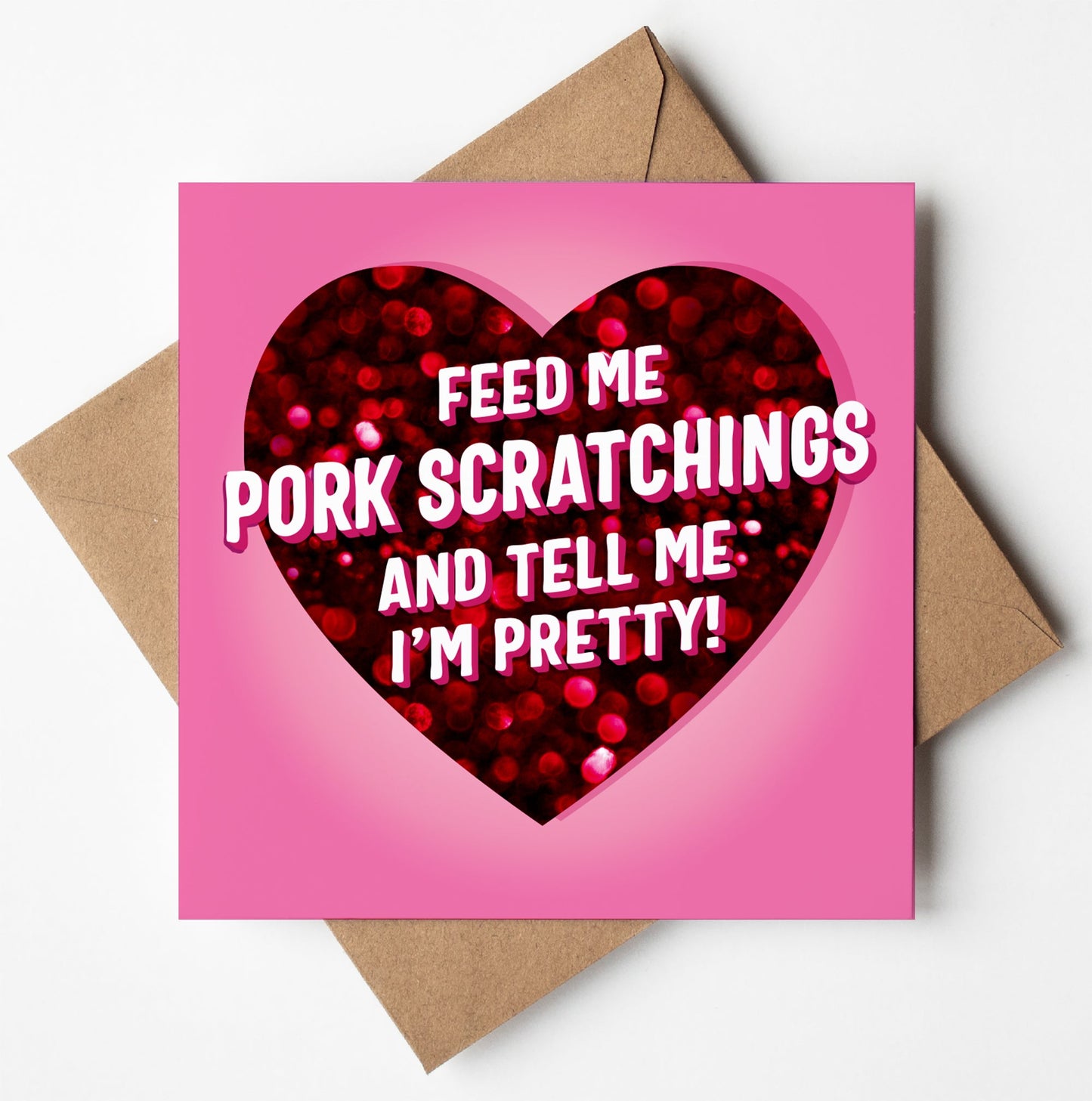 Titled "Feed Me Pork Scratchings And Tell Me I'm Pretty Love Card," this humorous Valentine's Day card showcases a playful message adorned with a glittery red heart on a pink background, complemented by a brown envelope.
