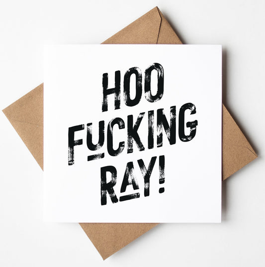 The Hoo Fucking Ray! Harlem Card, a white card featuring bold black text that reads "HOO FUCKING RAY!", is set on a brown envelope, making it an ideal sweary congratulations card. It comes packaged in a biodegradable bag for eco-friendly delivery and offers worldwide shipping.