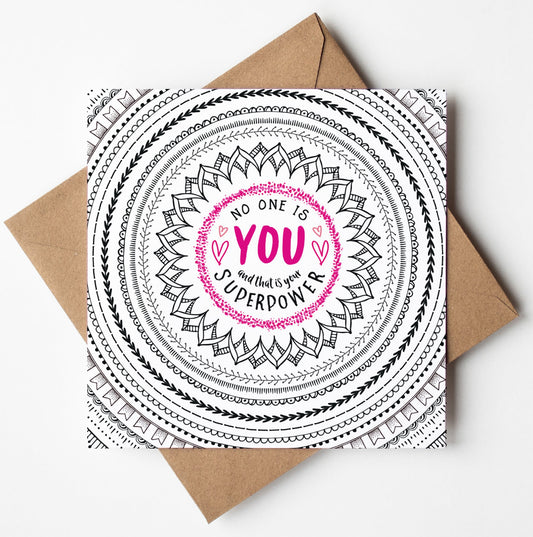 The "No One Is You Card" features an inspiring black and white mandala design with the empowering message "No one is you, and that is your superpower" highlighted in bright pink. This uplifting card is beautifully presented on a brown envelope against a clean white backdrop.