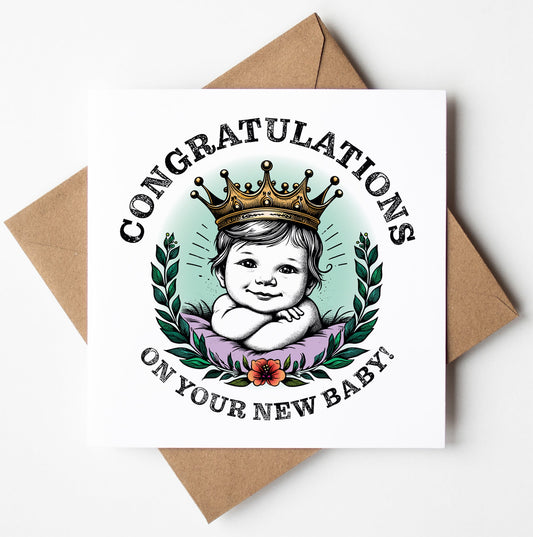 Introducing the "Congratulations On Your New Baby! Crown Card"—a delightful greeting card adorned with a crowned baby illustration encircled by a laurel wreath and accented by a delicate flower. The card features the joyful message, "Congratulations on your new baby!" and comes paired with a brown envelope.