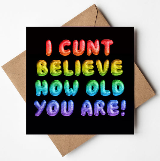 A brown envelope contains the "I Cunt Believe How Old You Are! Rainbow Font Card," featuring colorful, bold, stylized letters against a black background that exclaims, "I CUNT BELIEVE HOW OLD YOU ARE!