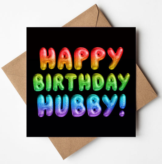 The "Happy Birthday Hubby! Rainbow Font Card" features a bold, balloon-like rainbow font against a striking black background, and includes a brown envelope for an eco-friendly gifting option, much like using a biodegradable bag.