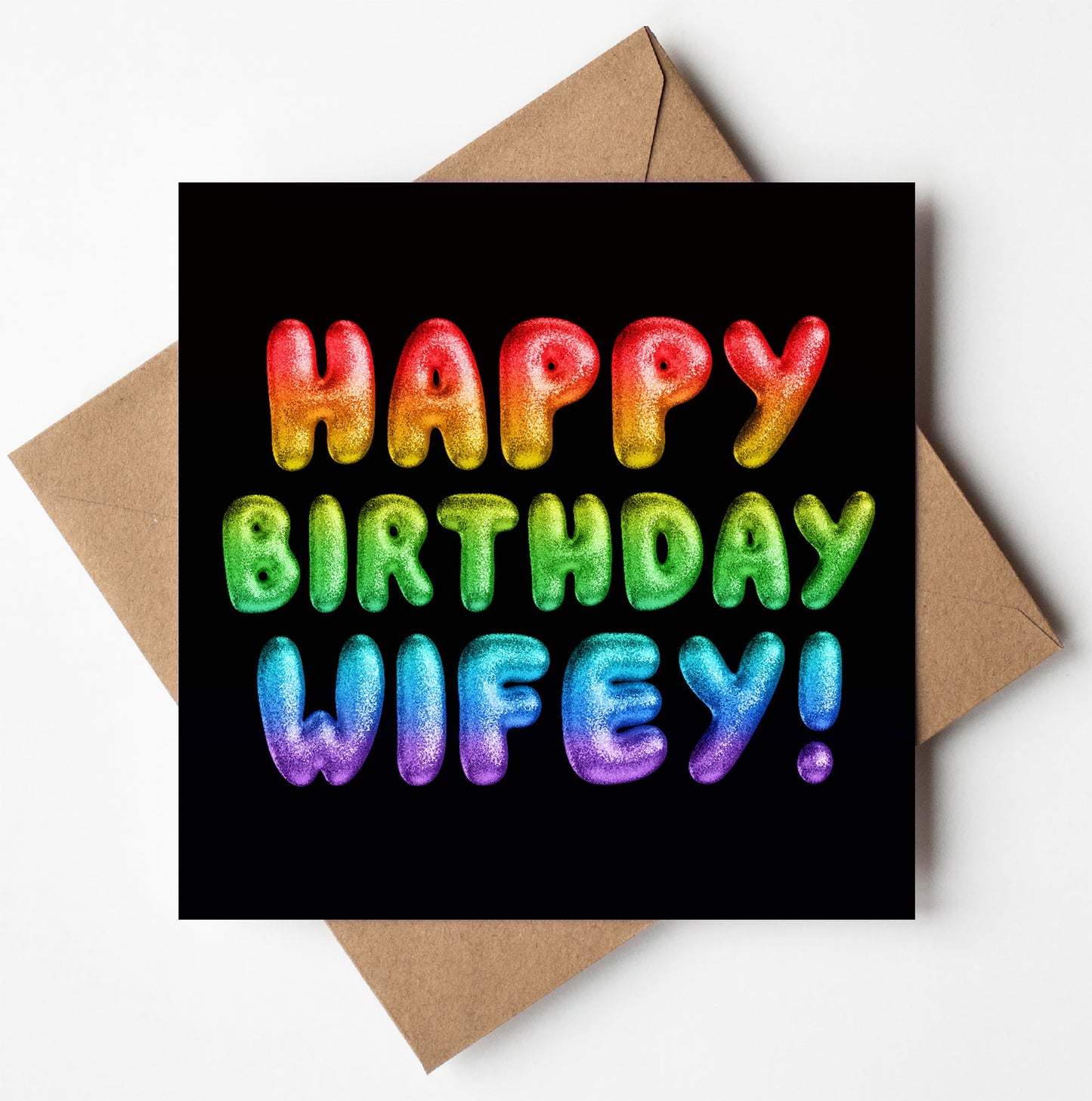 The "Happy Birthday Wifey! Rainbow Font Card" showcases a vibrant, multicolored message on a sleek black background, complemented by its elegant placement on a brown envelope.