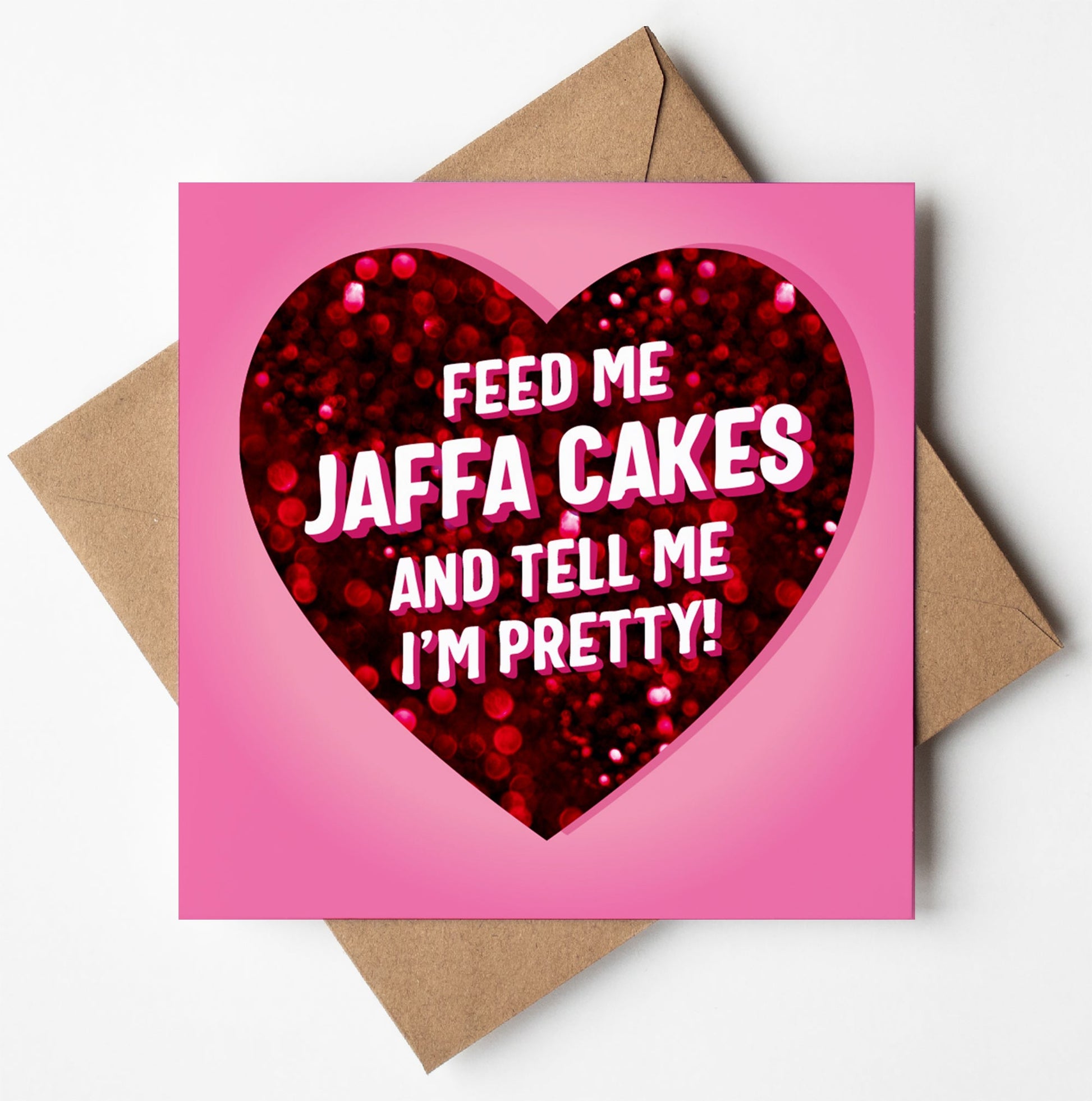 The "Feed Me Jaffa Cakes And Tell Me I'm Pretty" love card for Valentine's Day showcases a heart-shaped design adorned with red glitter. The humorous message inside the heart says, "Feed me Jaffa Cakes and tell me I'm pretty!" and comes with a brown envelope.