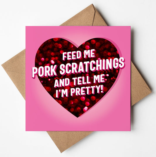 Titled "Feed Me Pork Scratchings And Tell Me I'm Pretty Love Card," this humorous Valentine's Day card showcases a playful message adorned with a glittery red heart on a pink background, complemented by a brown envelope.