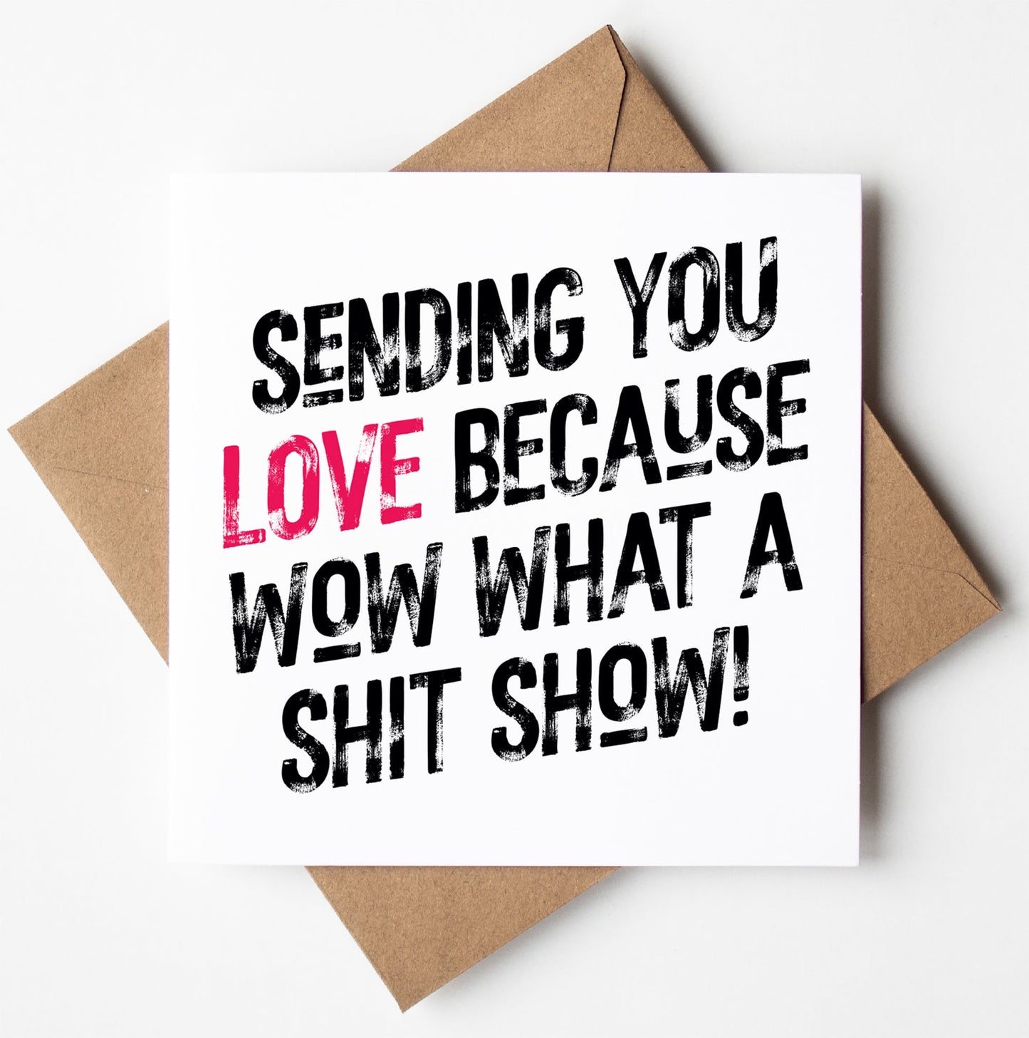 Inside a biodegradable bag lies the "Sending Love Because Wow What A Shit Show! Harlem Card," featuring an envelope with striking black text: "Sending you love because wow what a shit show!" The word "love" is highlighted in pink, primed for worldwide shipping.