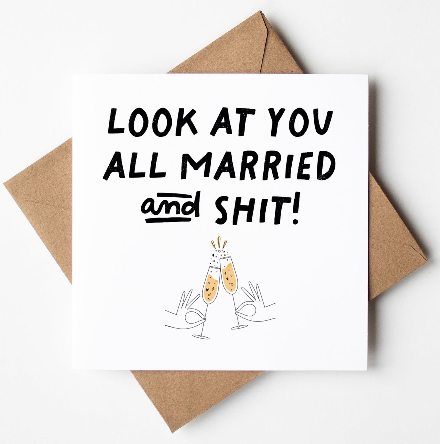 The "Look At You All Married and Shit!" Card, adorned with two illustrated hands clinking champagne glasses and carrying the celebratory message, is tucked inside a brown envelope crafted from biodegradable materials. It's an ideal way to send your congratulations while being kind to the planet!