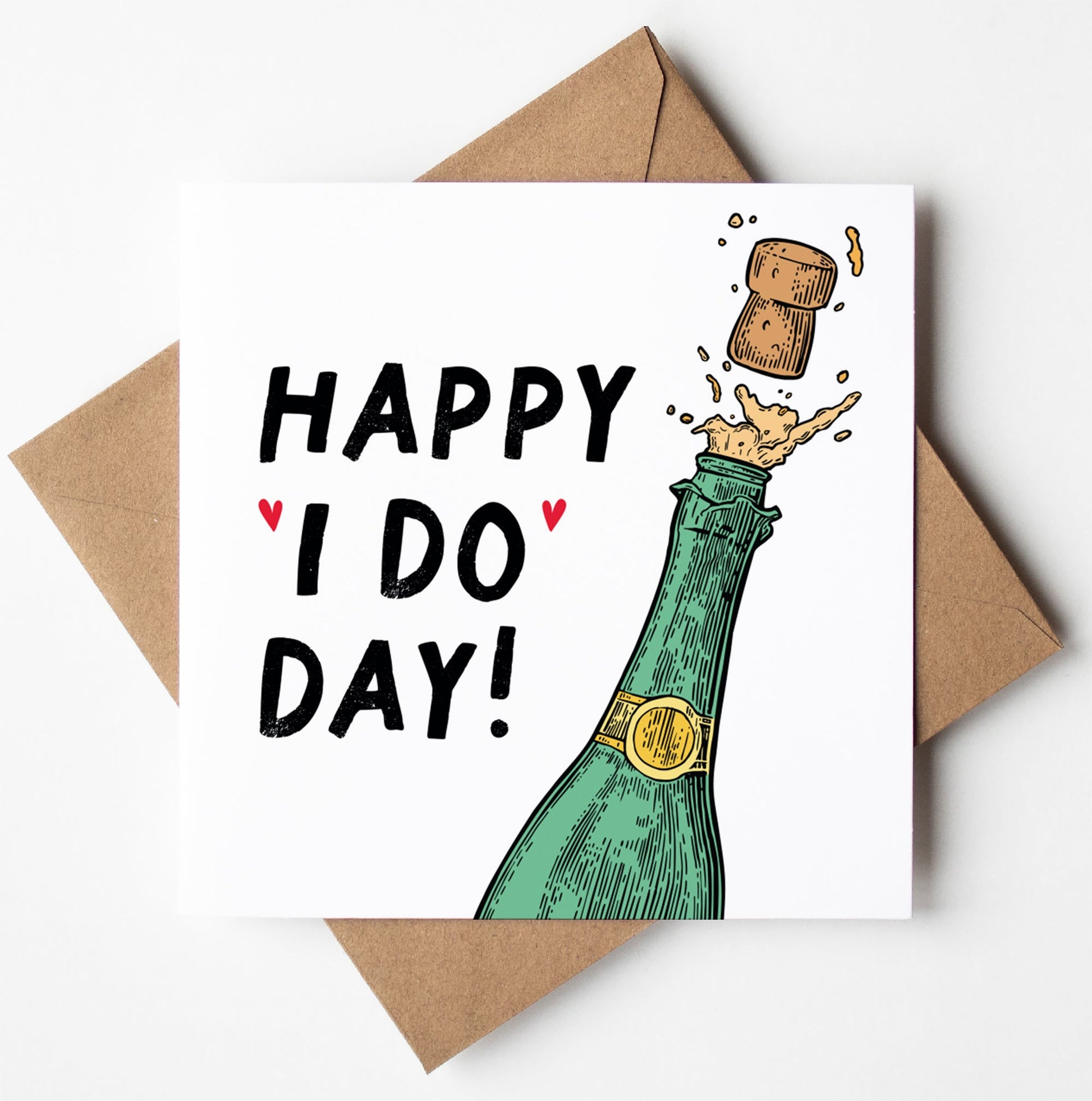 The "Happy 'I Do' Day Wedding Card" features an illustration of a champagne bottle popping, with a cork soaring through the air as bubbles dance around. The text reads "Happy I Do Day!" and is decorated with charming hearts. This wedding card comes nestled in a brown envelope, ready for worldwide shipping and protected by a biodegradable bag.