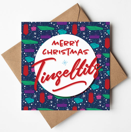 Introducing the "Merry Christmas Tinseltits Pressies Navy Card": This festive card boasts a blue background adorned with colorful gifts and snowflakes. At the center, you'll find a white circle displaying "Merry Christmas Tinseltits" in vibrant red text. It’s available with worldwide shipping and comes presented on top of a brown envelope.