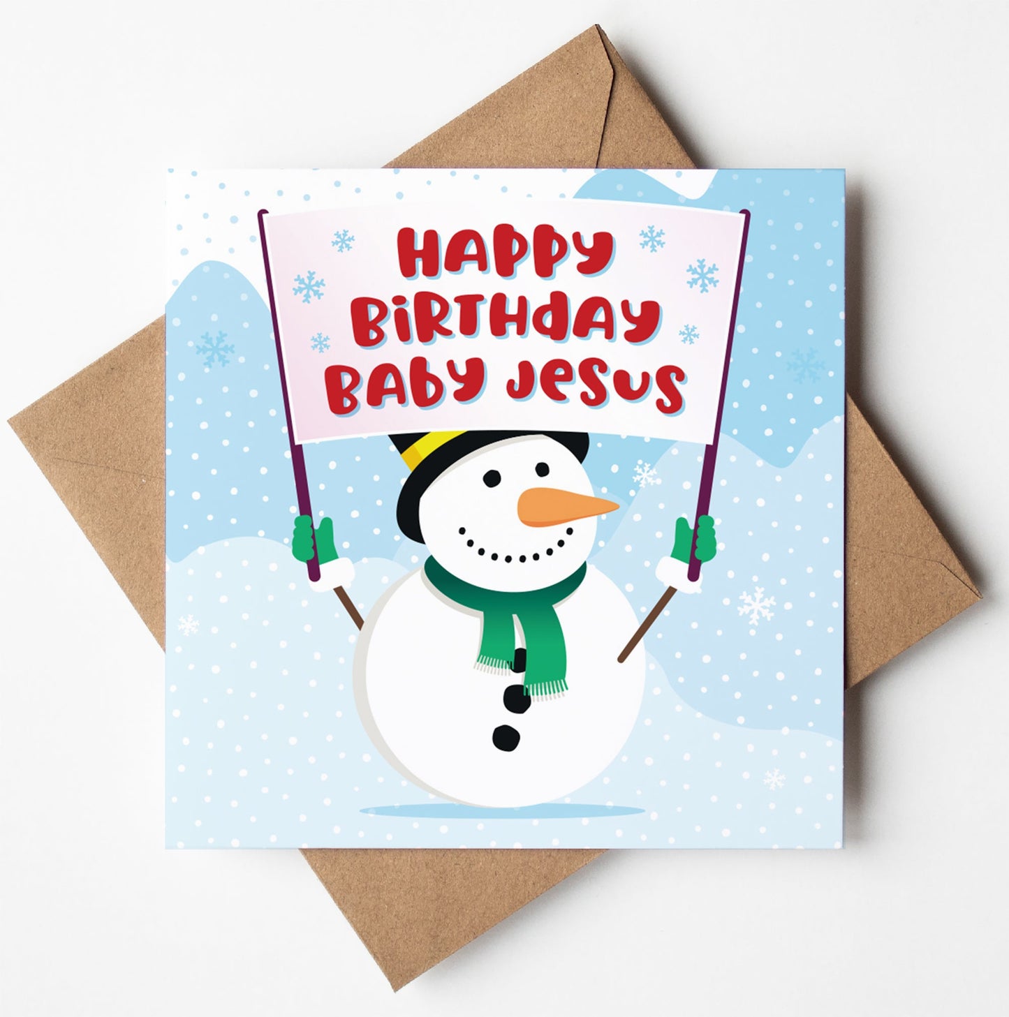 The Happy Birthday Baby Jesus Christmas Card depicts a snowman holding a banner with the same message amidst falling snowflakes and a snowy landscape. It is paired with a brown envelope, available for worldwide shipping, and packaged in an eco-friendly biodegradable bag.